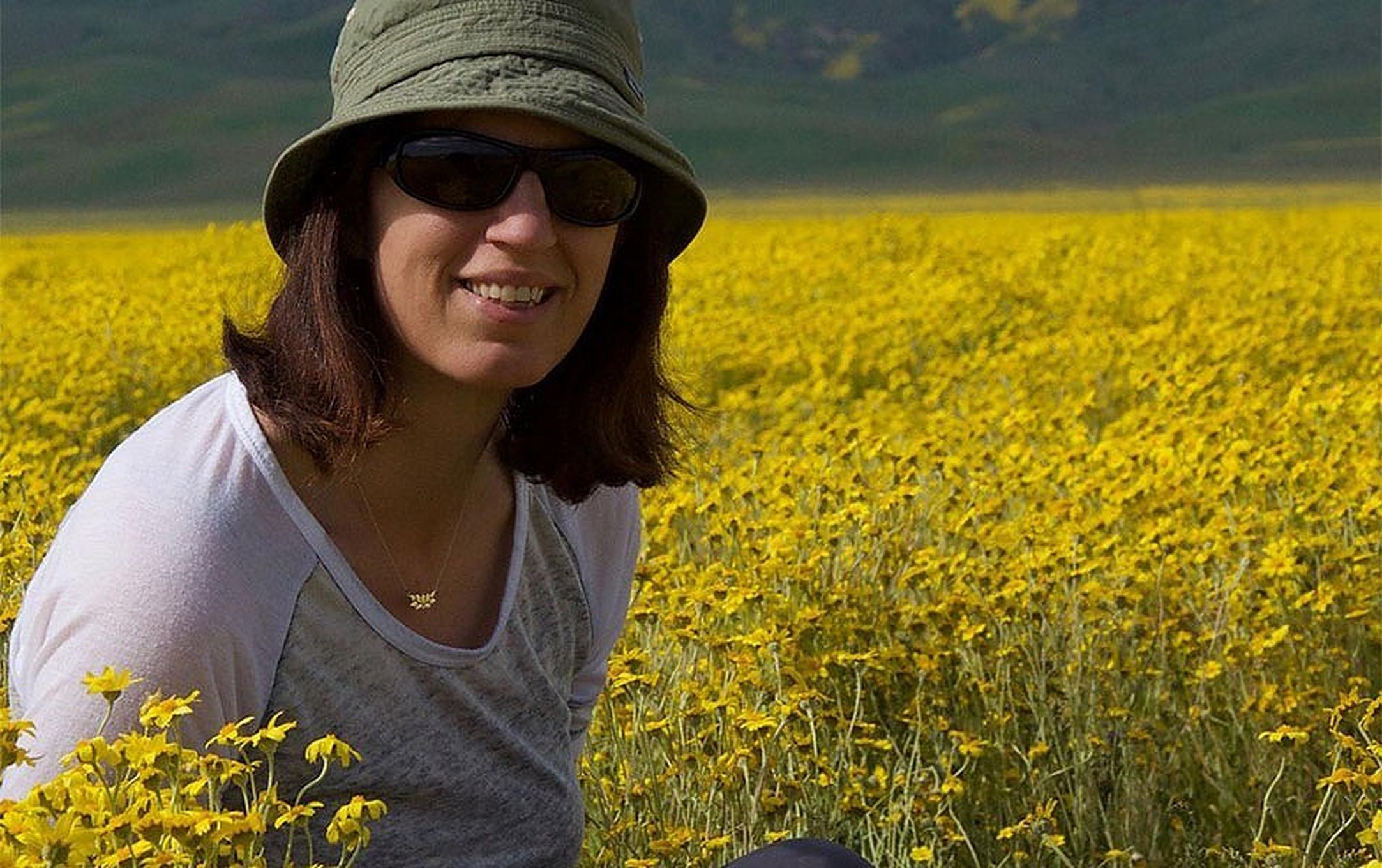 A woman sits on a trail in a field of yellow wildflowers at Carrizo Plain National Monument during the 2017 spring superbloom.