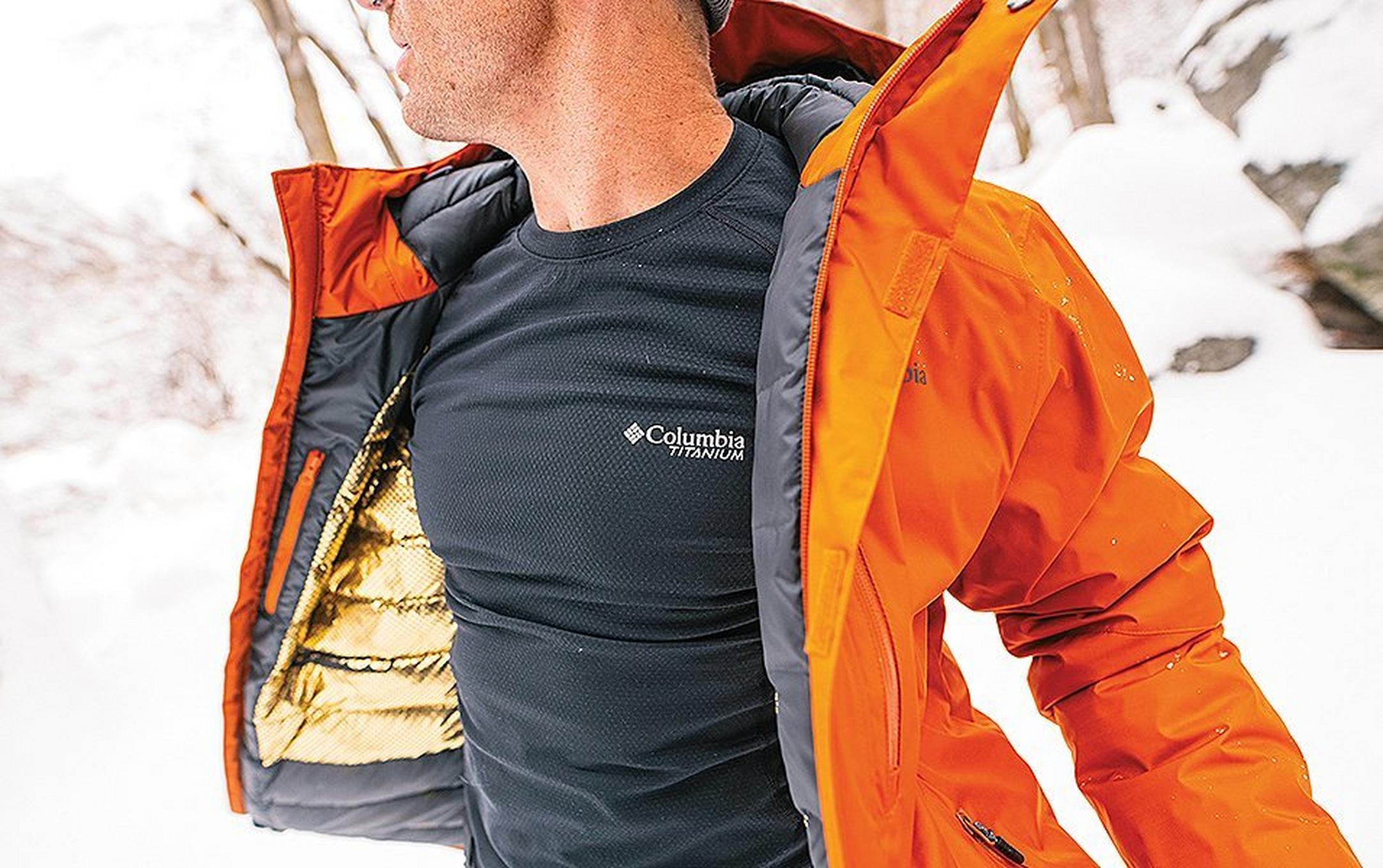 Man with coat open in a snowy landscape.