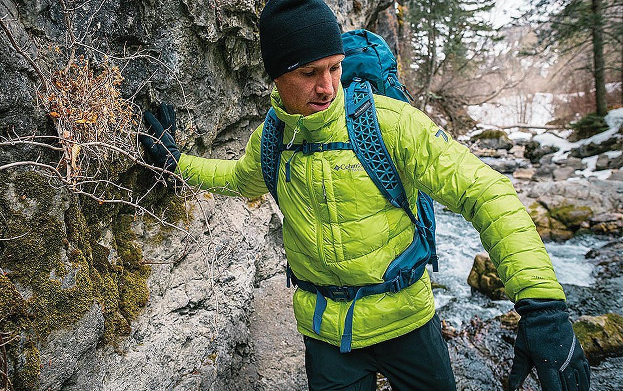 A warmly dressed man hiking through the woods.