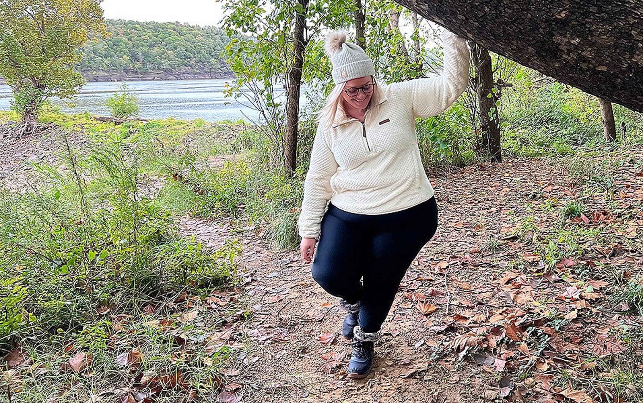 A women standing under a tree near a river.