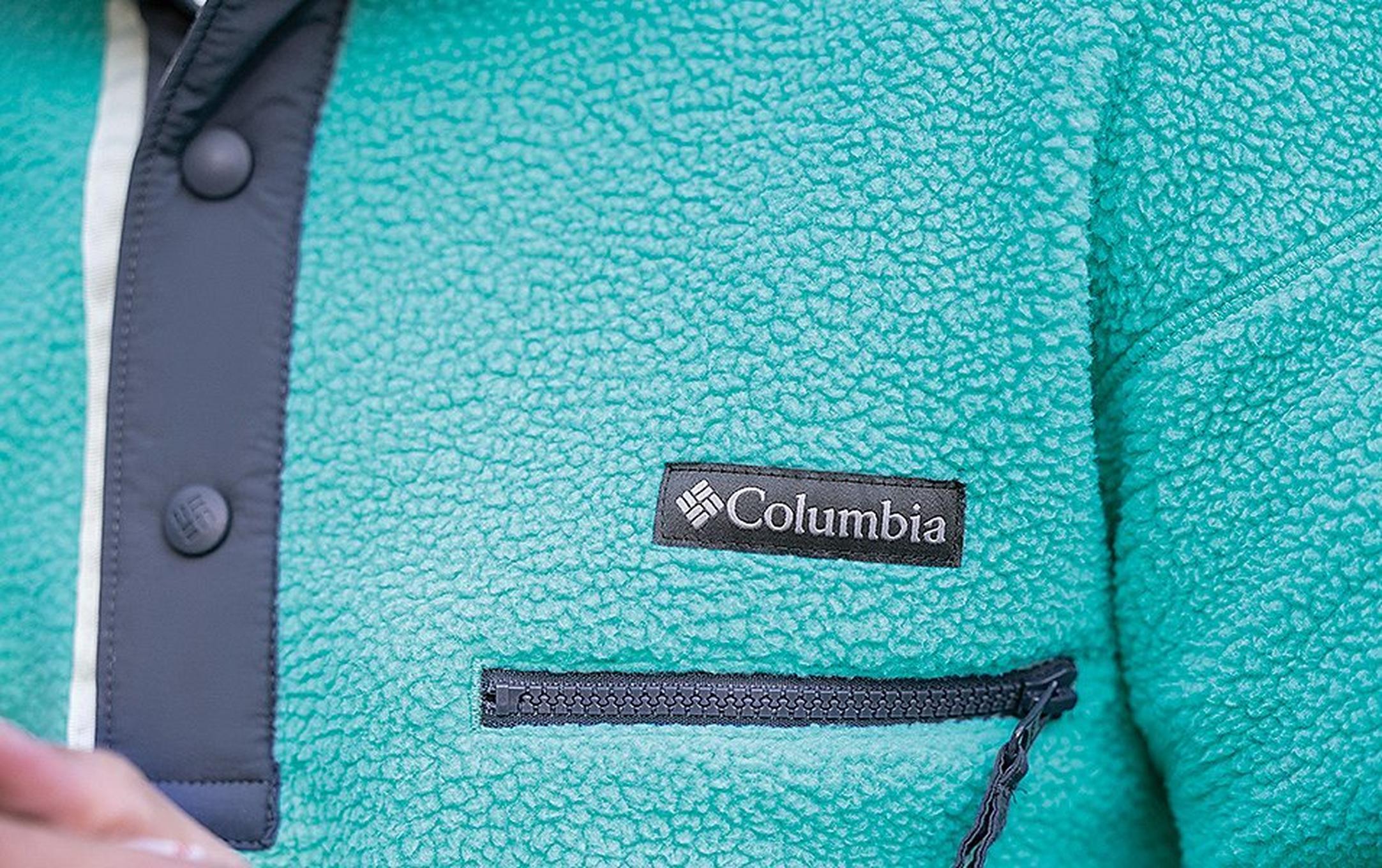 A close-up shot of the upper pocket of a blue Columbia Sportswear fleece.
