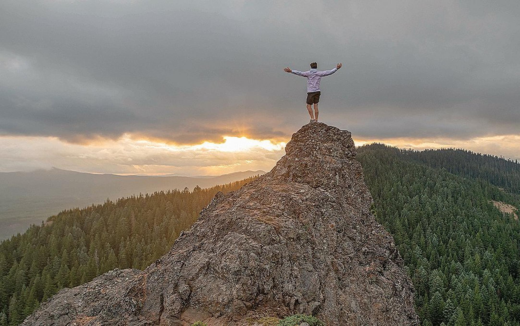 Man on top of mountain at sunset.