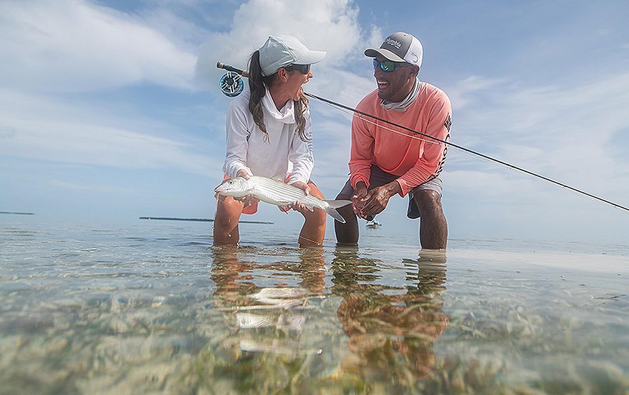 Two people fishing in clear waters.