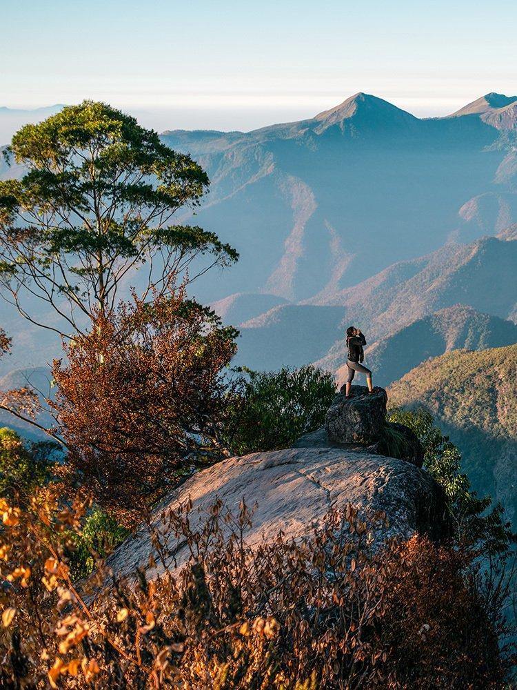 Person hiking in the distance surrounded by a mountain range