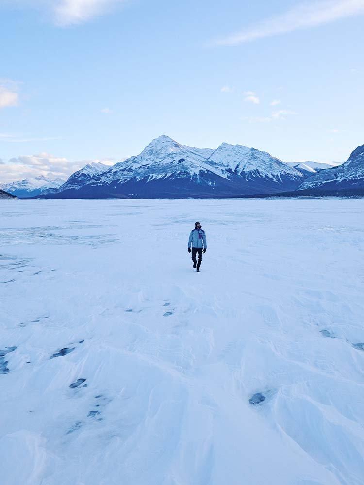 Person on the edge of a snowey cliff with skis on their back.