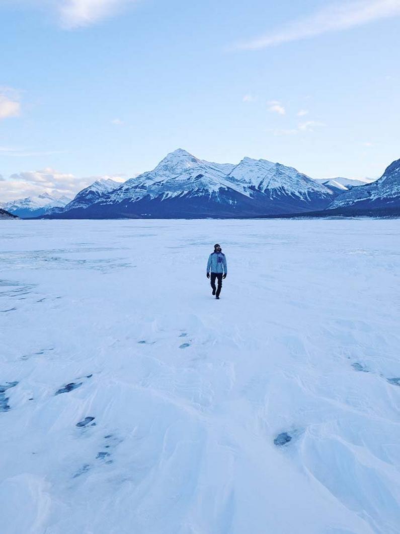 Person walking on snow surrounded by a mountain range.