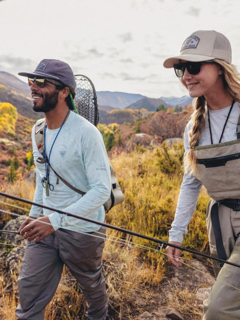 Two people walking in a field with their fishing gear