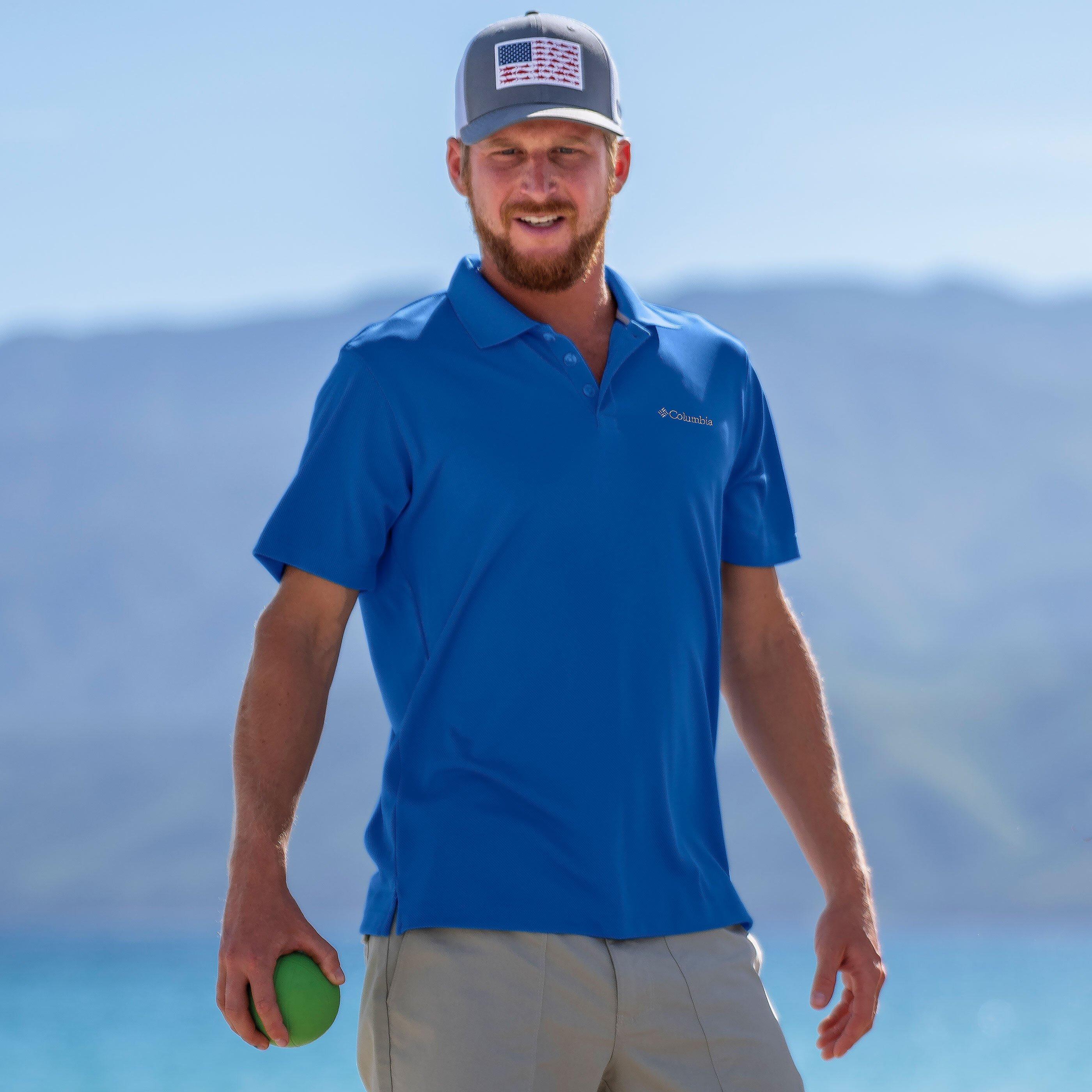 A man on the beach playing a game wearing a polo shirt