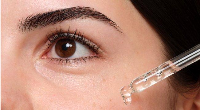 Person applying serum under eye with dropper