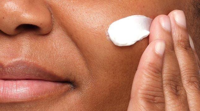 Model swiping Natural Moisturizing Factors + HA across her cheek