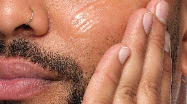Close up crop of male model with beard applying lightweight serum
