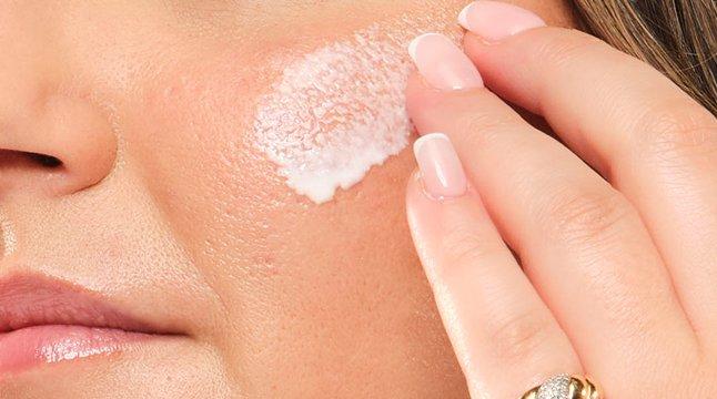 Closeup of model applying UV Filters SPF 45 with its lightweight serum texture.