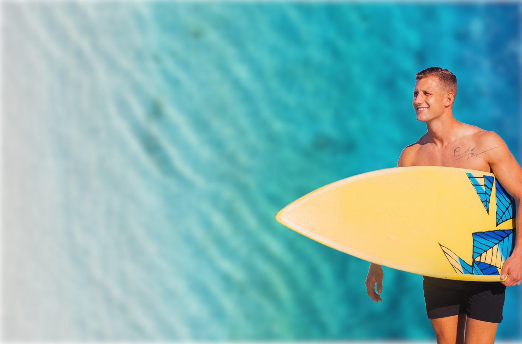 a man in black swim trunks holding a yellow surfboard