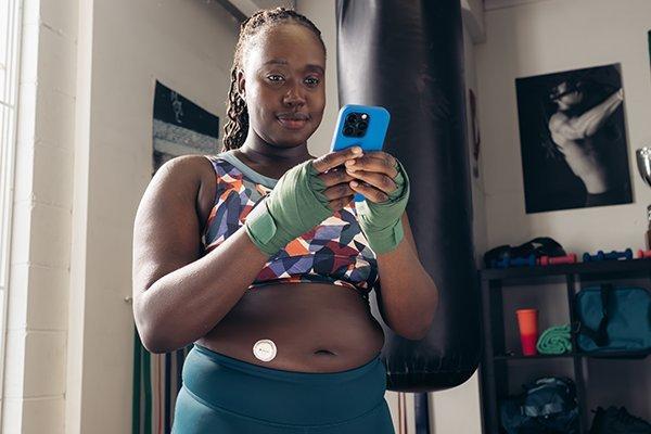 Woman exercising, stops to check her glucioe readings.