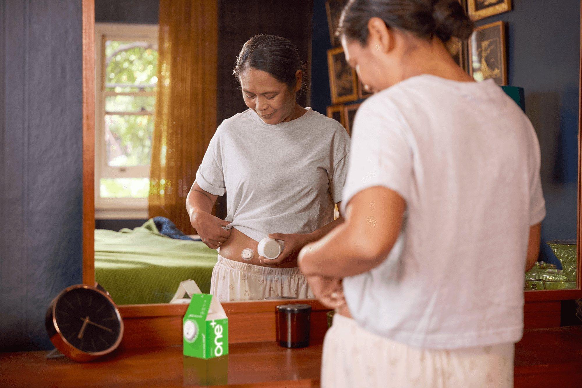 woman applying the Dexcom ONE+ sensor
