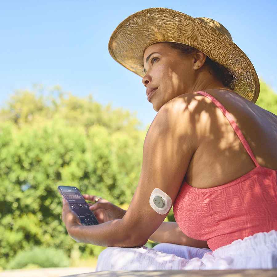 woman wearing stelo and holding smart phone with stelo app