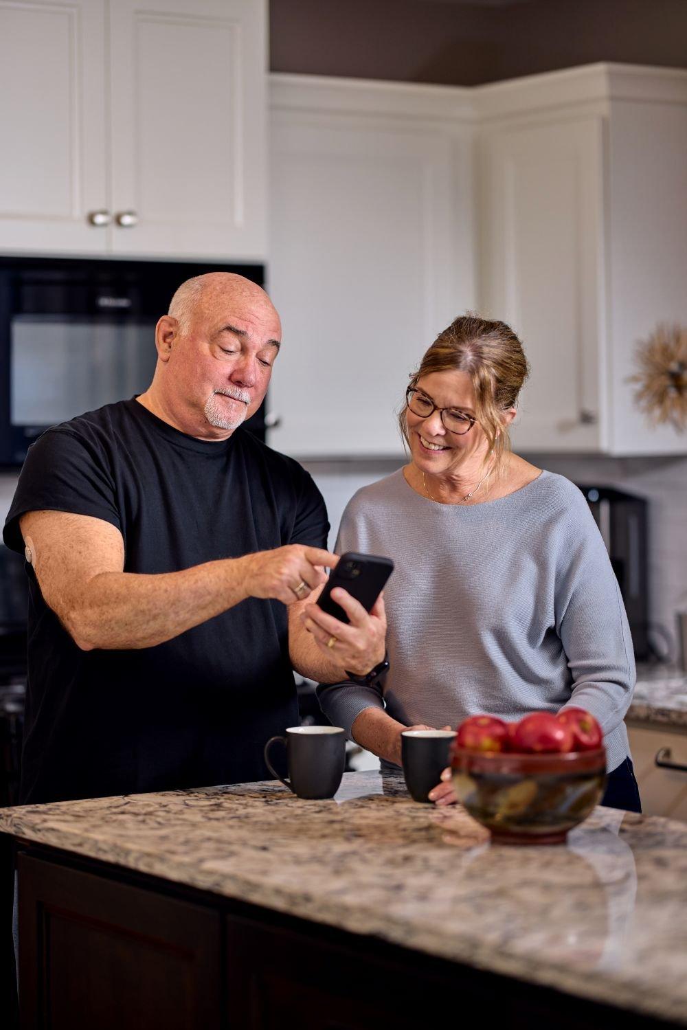 Dean and Barb in their kitchen looking at his phone