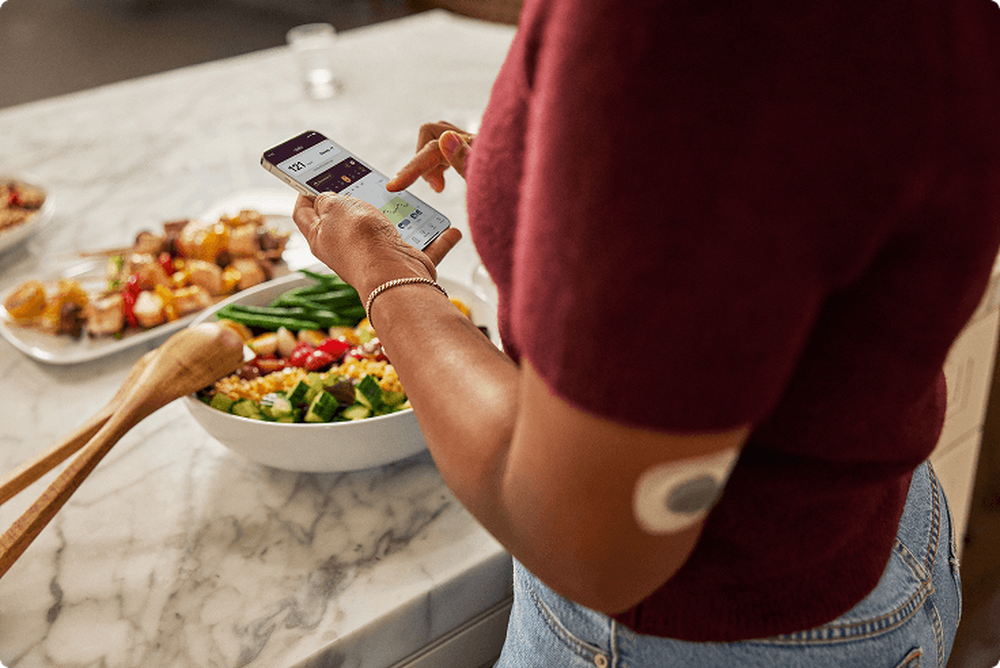 Woman wearing sensor while looking at her phone in the kitchen