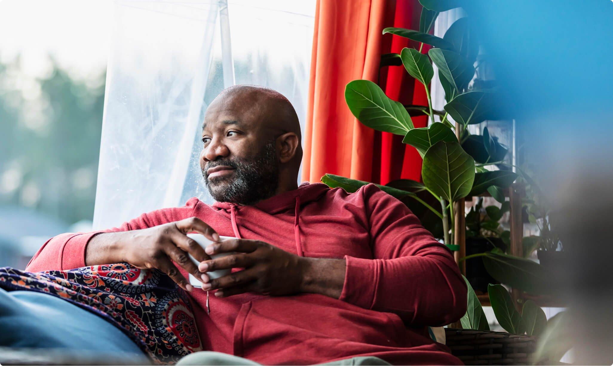 Man drinking from a mug looking out his window
