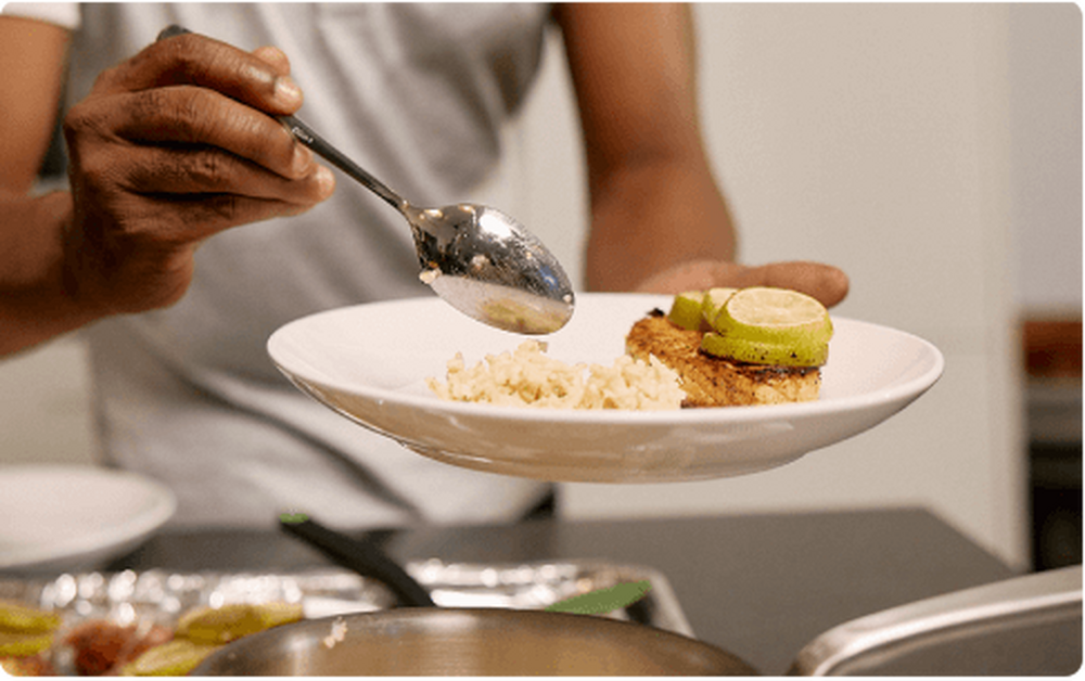 Person eating a meal with rice, fish and lime slices.