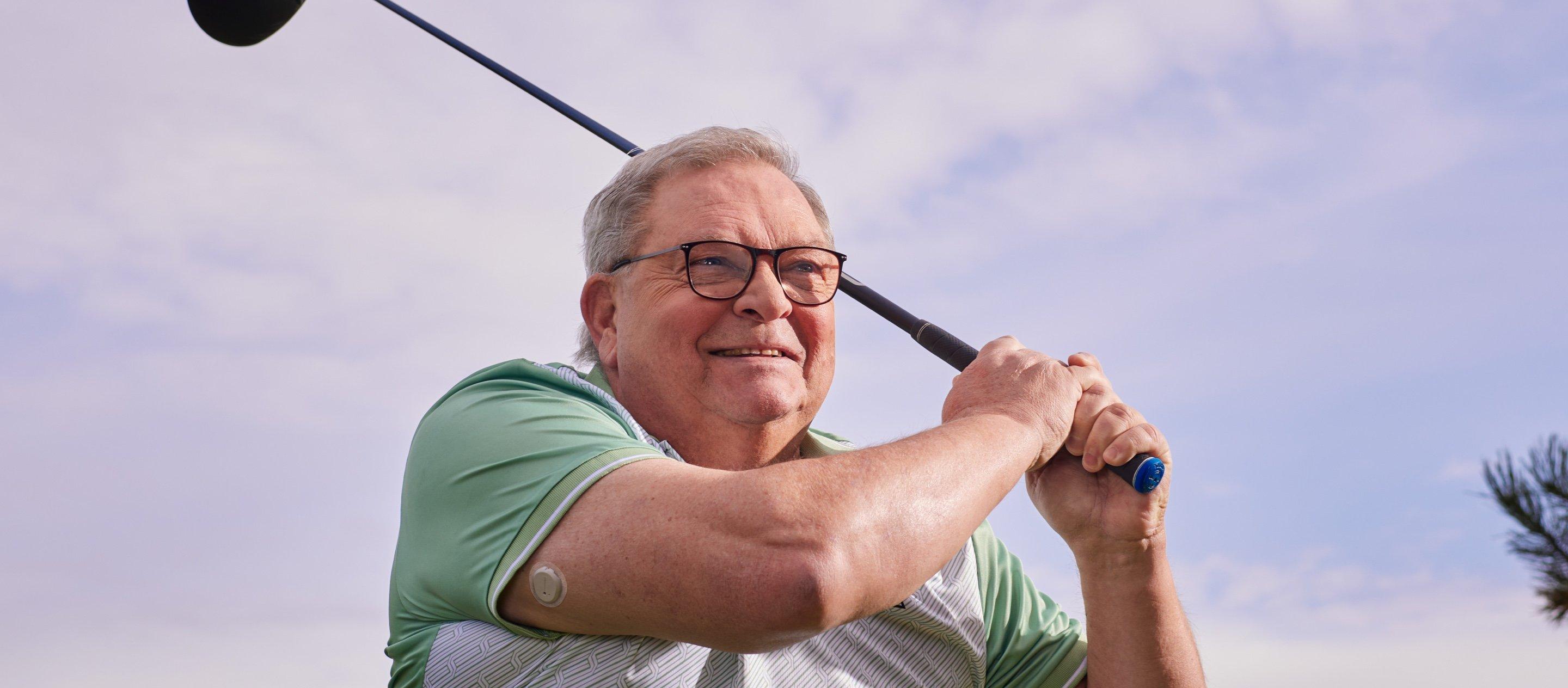 persona, kas spēlē golfu ar cgm uz rokas