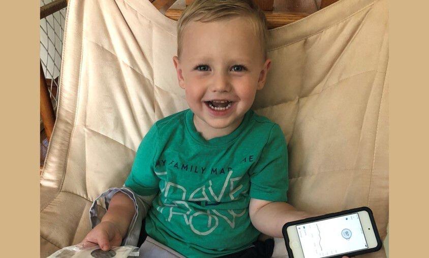 Piet smiling and holding phone with Dexcom app