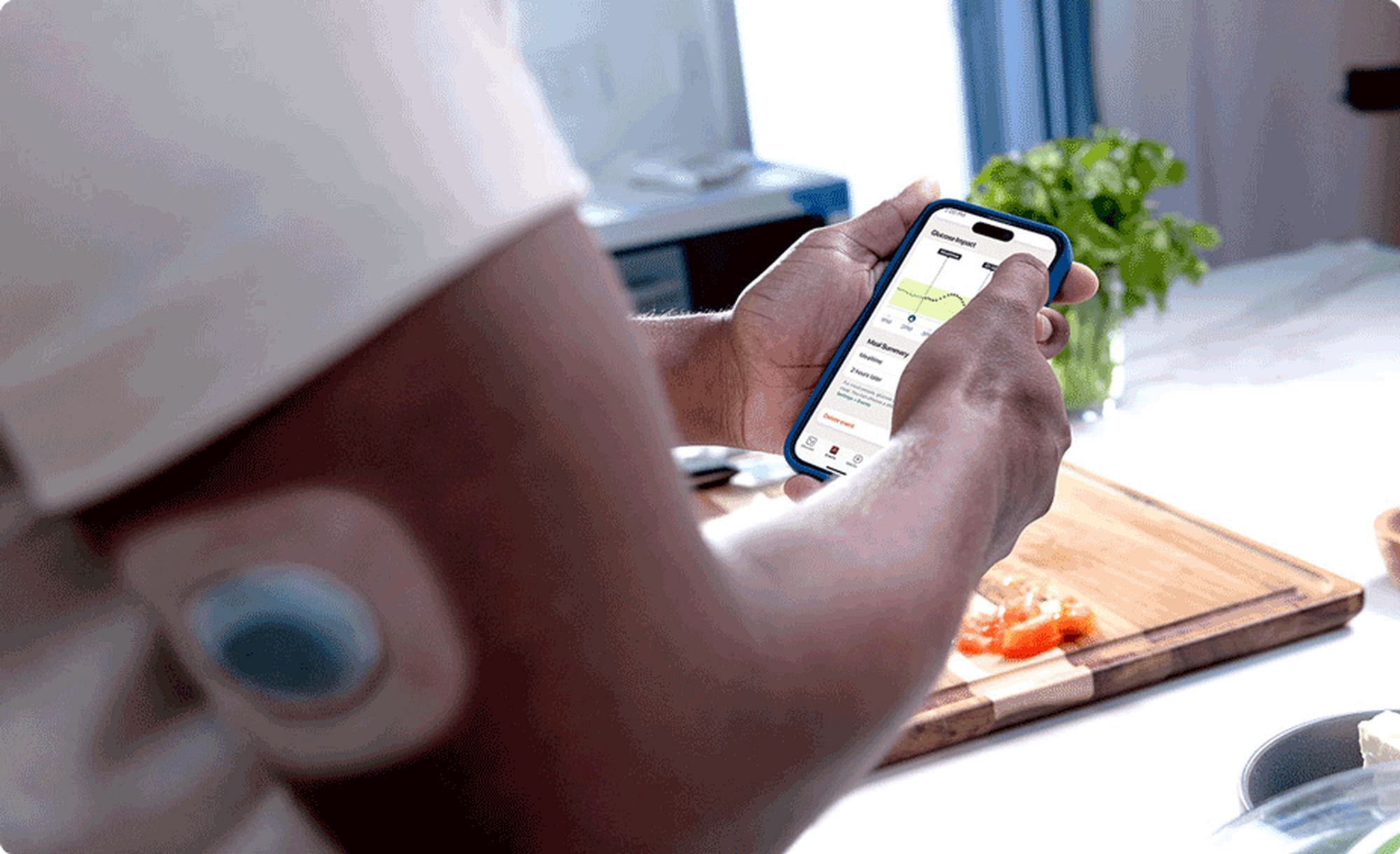 Woman checking stelo app while cutting vegetables