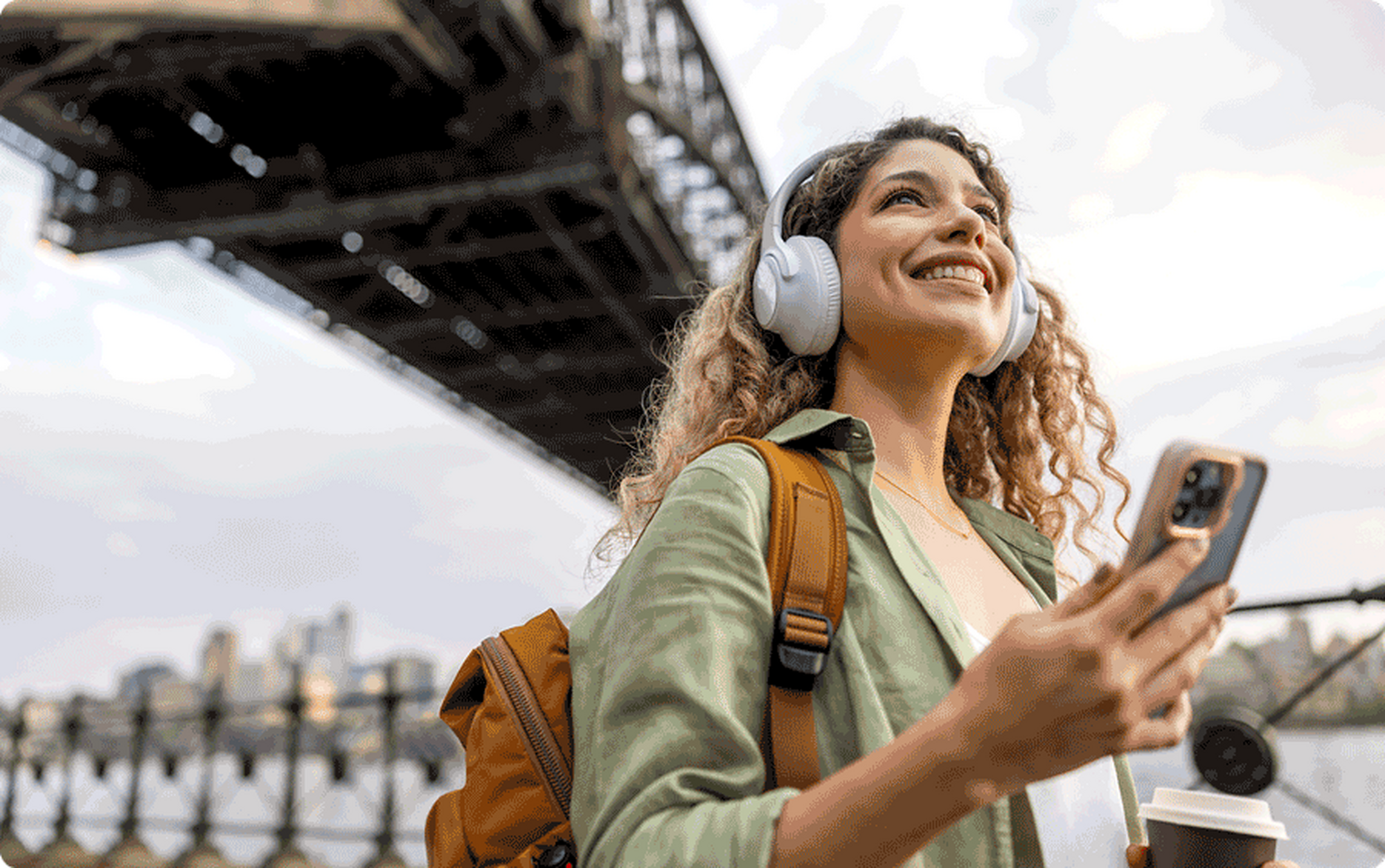 woman walking with headphones on holding up her phone