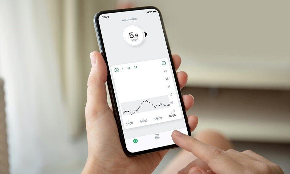Osoba koja pokazuje telefon s aplikacijom Dexcom na telefonu