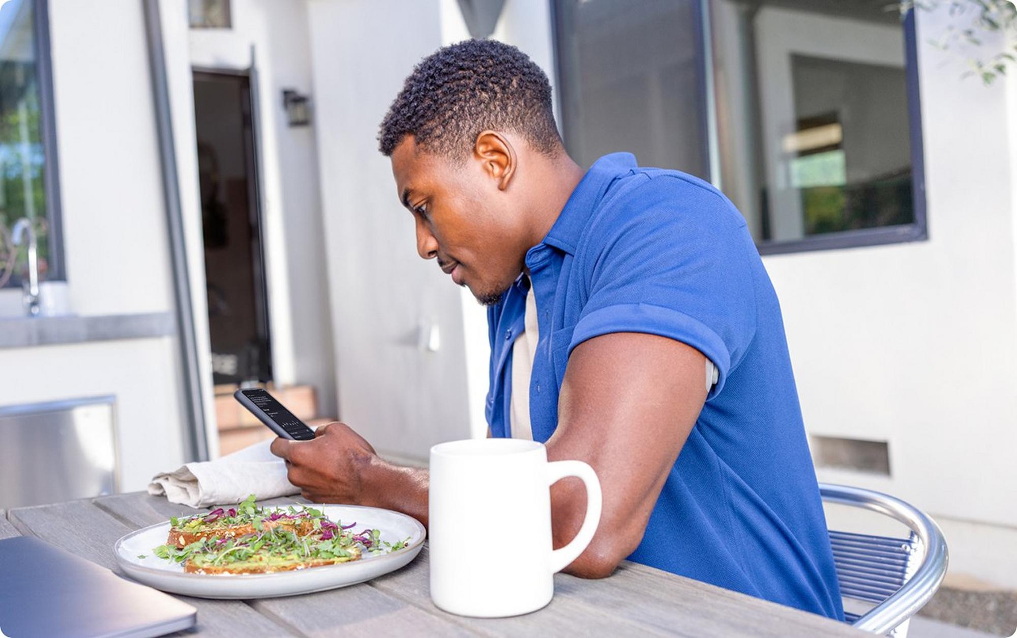 man holding phone eating food