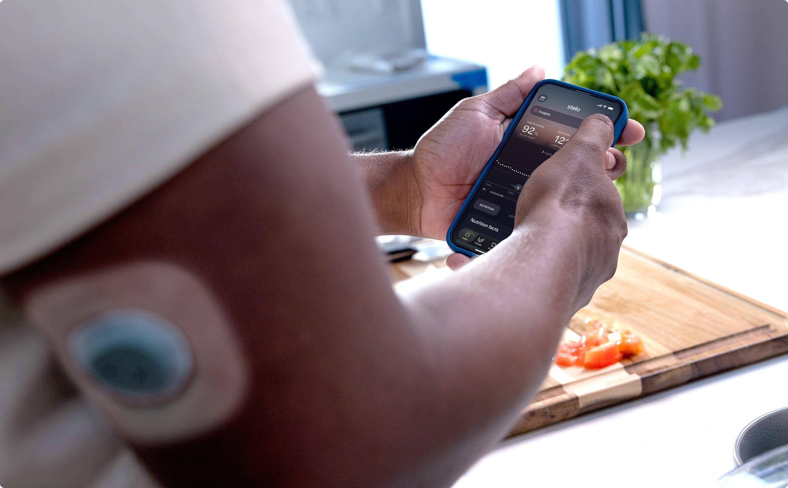 woman holding stelo app screen "what impacts my glucose"