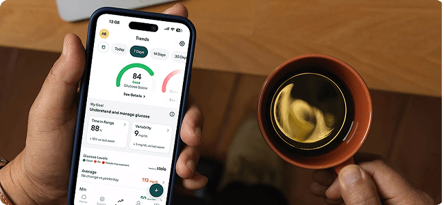 Person holding a drink and a phone with health app open showing readings 