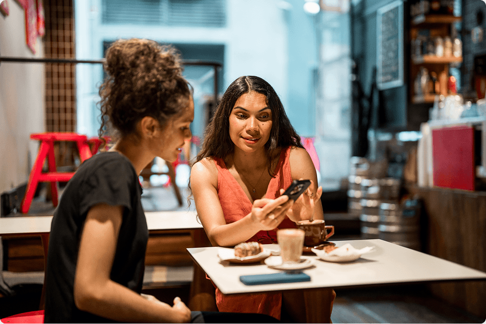 Friends in a coffee shop looking at something on their phone