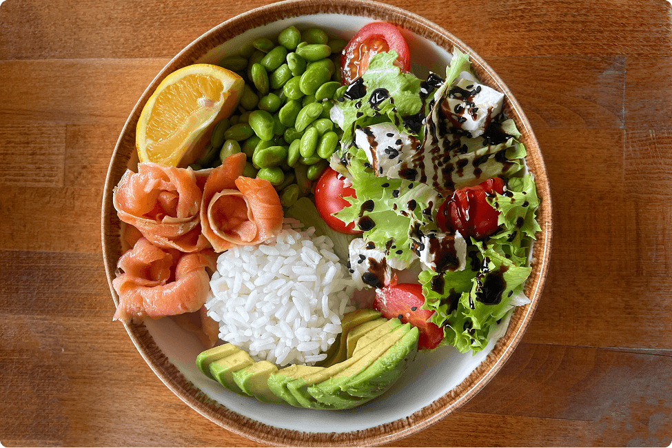 Rice, beans, letuce, tomatoes, avacado, and a lemon in a bowl