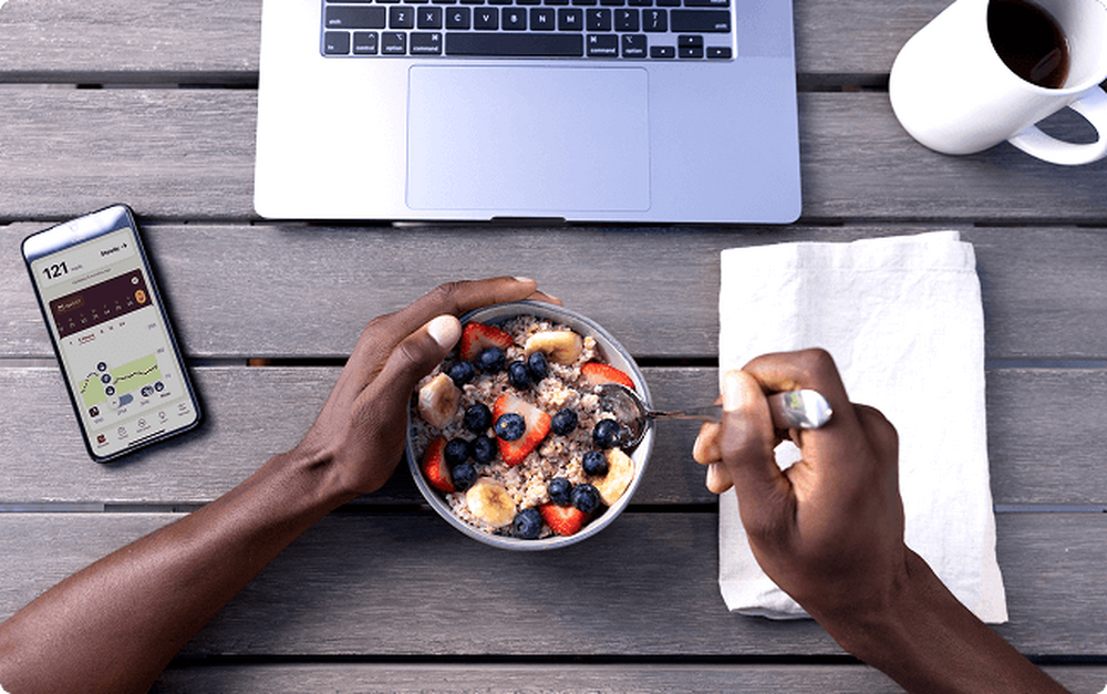 Person eating a fruit and oats bowl at their computer