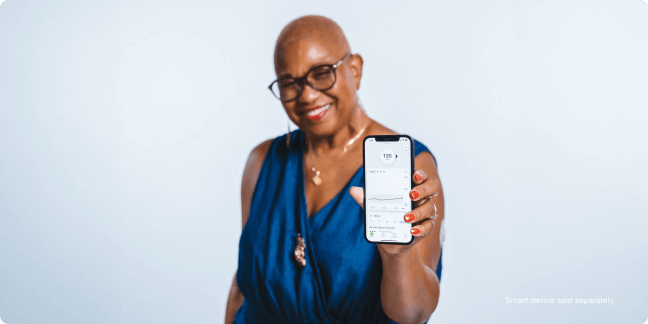 Kim holding up her glucose readings on a smartphone - smart devices sold separately