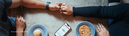 Two people holding hands with a phone in the center showing glucose levels - Smart device sold separately