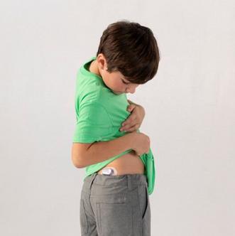 Boy in green shirt looking at Dexcom device on his bottom
