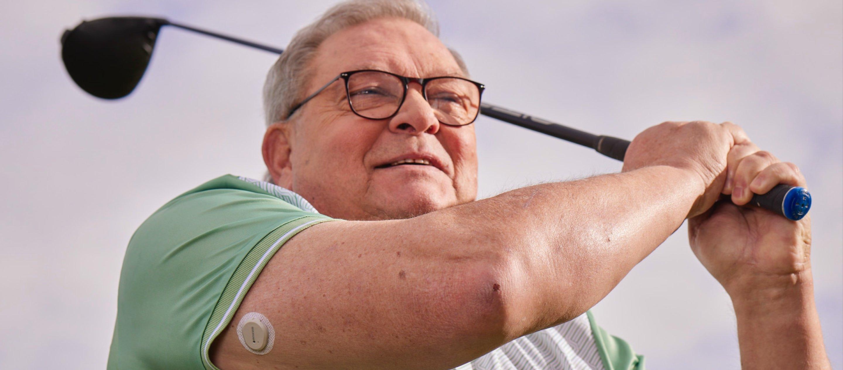 persona, kas spēlē golfu ar cgm uz rokas