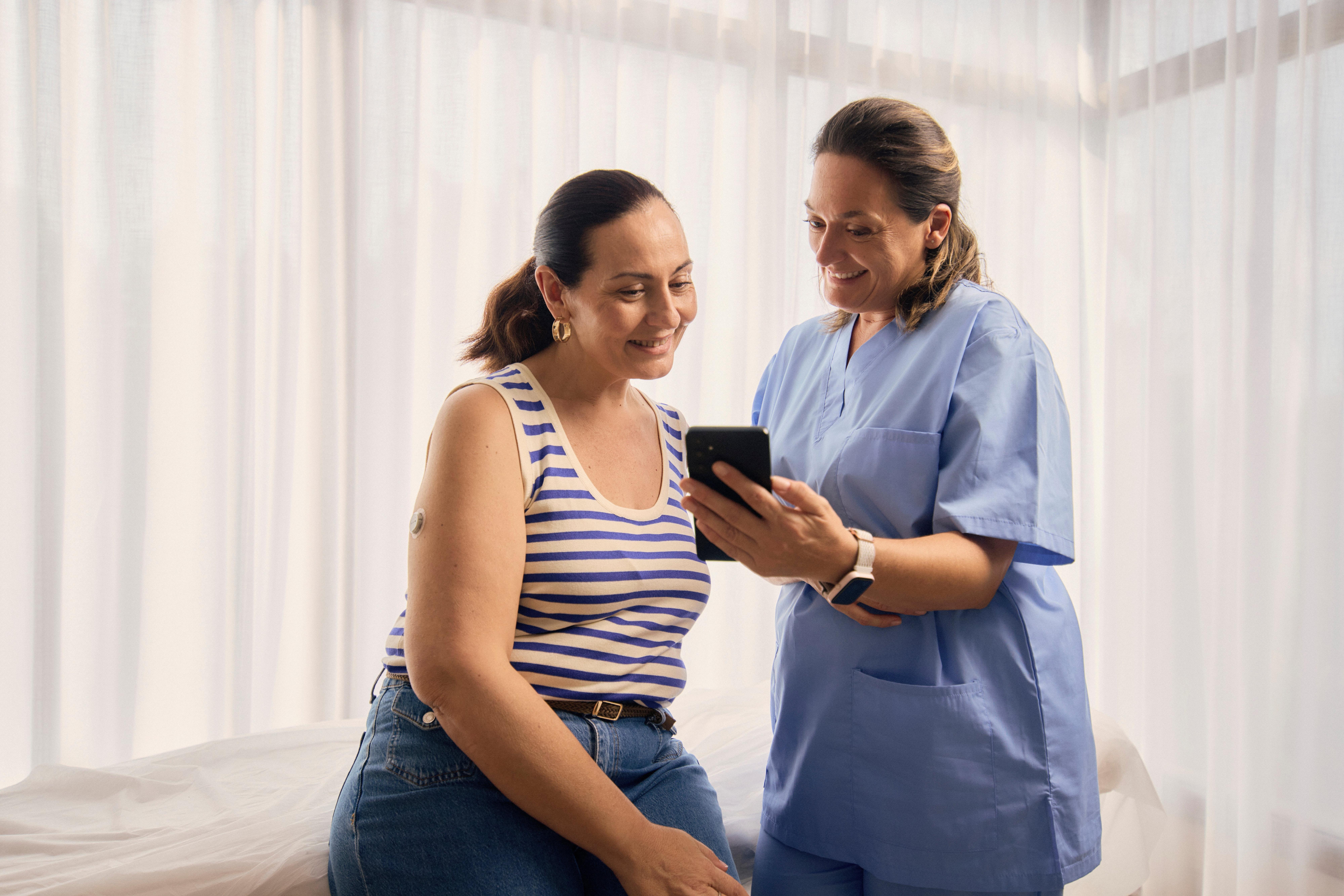 Medizinische Fachkraft zeigt dem Patienten Smartphone-Informationen
