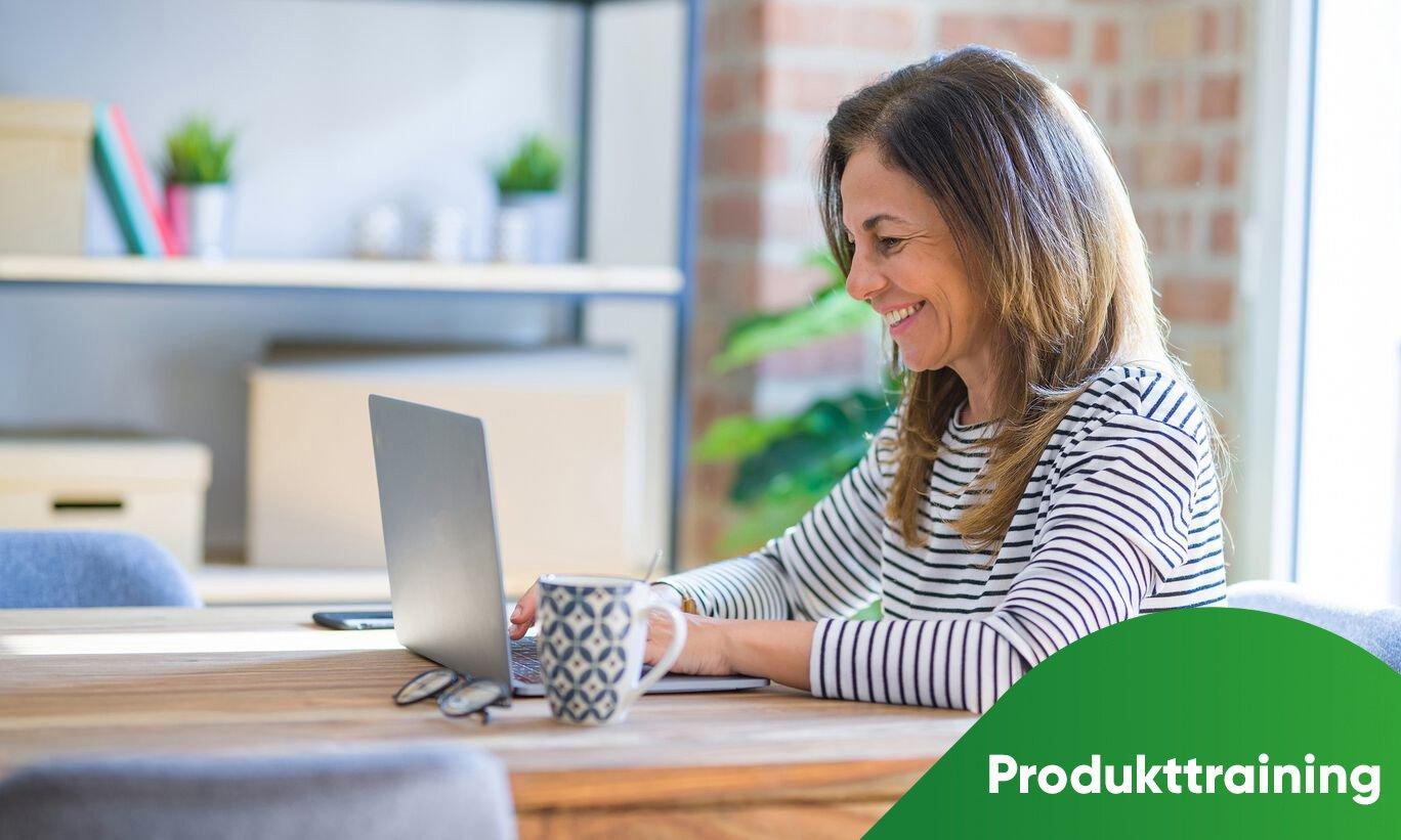 Lächelnde ältere Frau sitzt an einem Tisch vor einem Laptop