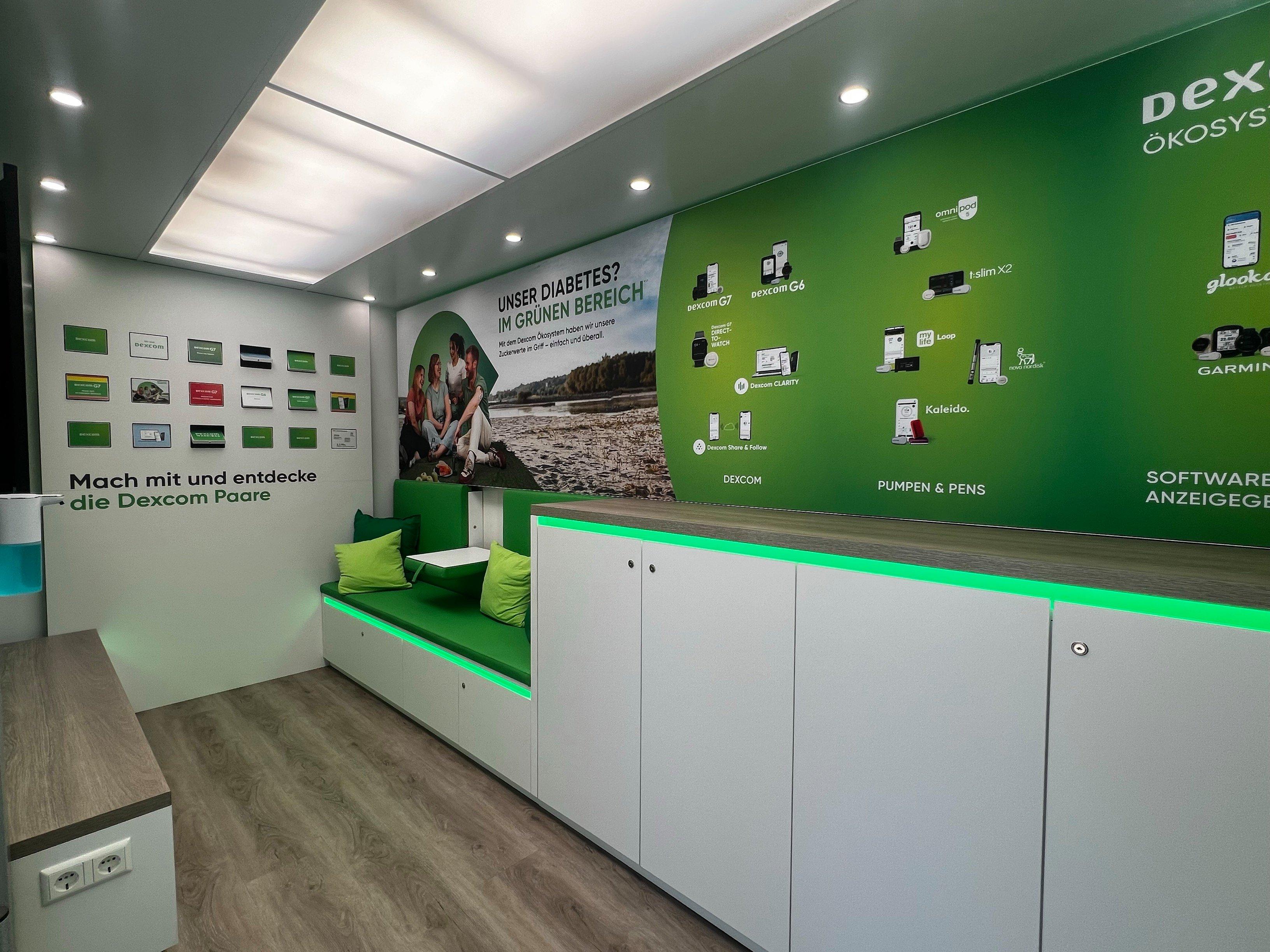 Das Innere des Roadshow-Trucks wird mit indirekter Belichtung dargestellt. Die Wand ist grün, auf der Wand ist ein Bild von Menschen mit Diabetes. Sie lächeln und haben ein Picknick. An der Wand steht: Mein Diabetes? Im grünen Bereich. Außerdem sieht man die vielen Insulinpumpenpartner von Dexcom und ein Memory-Spiel mit Dexcom-Produkten, die die Blutzuckermessung ersetzen sollen. 