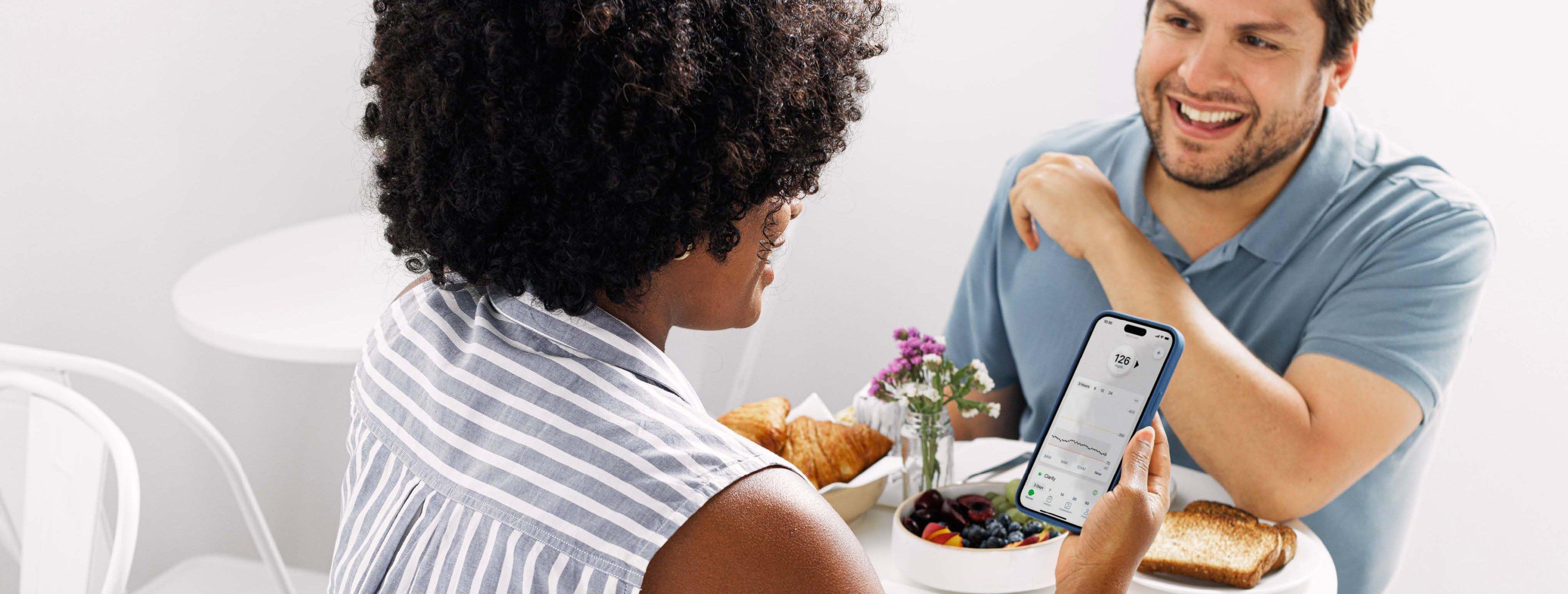 Woman reading her glucose levels on the dexcom CGM app while having lunch