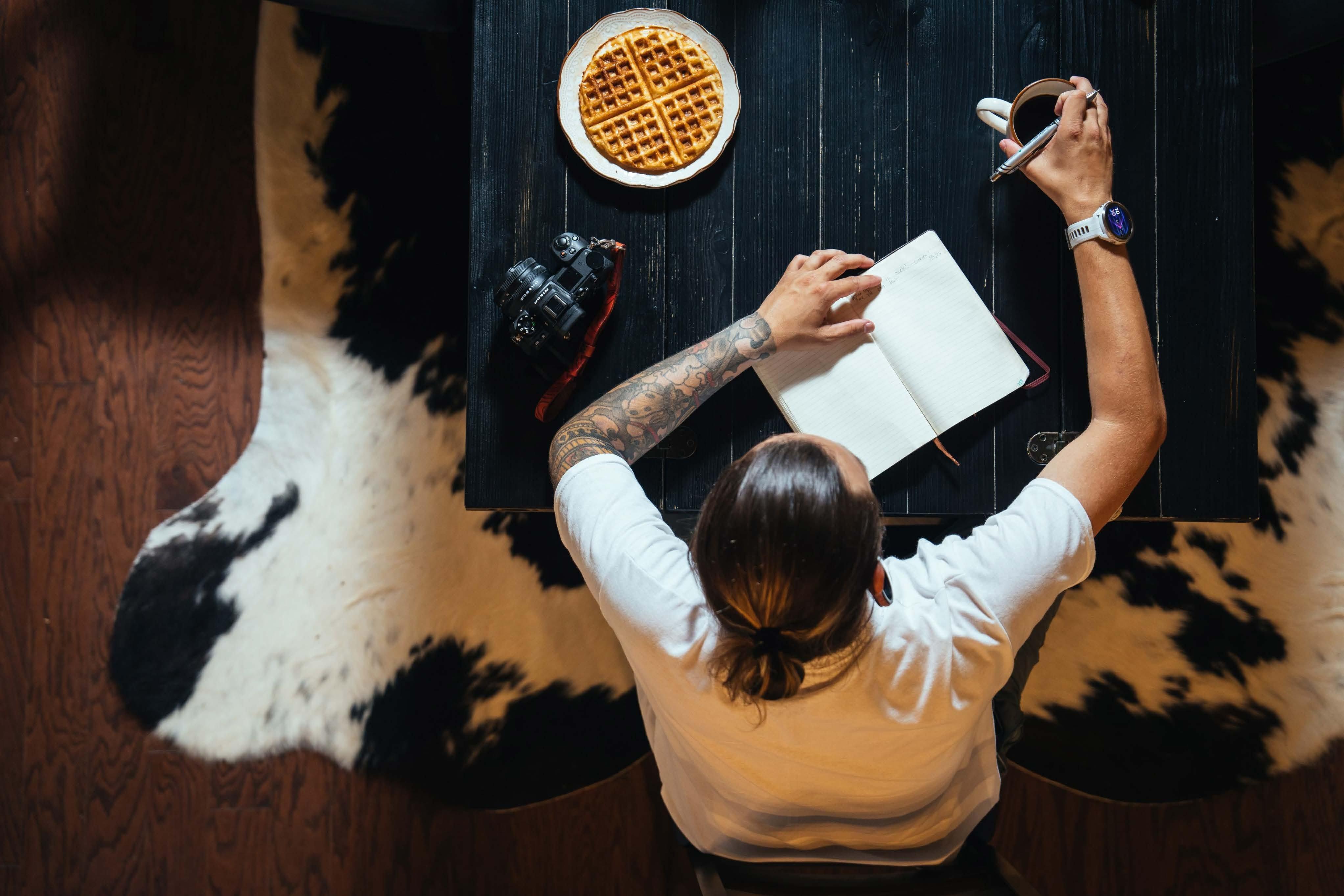 person with empty notebook and breakfast