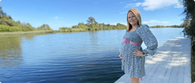 Devon on a dock holding baby bump