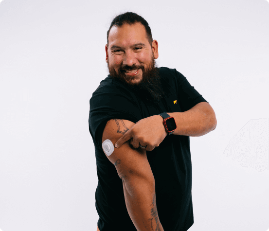 Dexcom Warrior Carlos Gonzalez smiling and pointing to a dexcom sensor on his arm