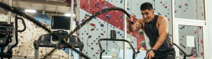 Man doing battle rope exercise while working out in a gym
