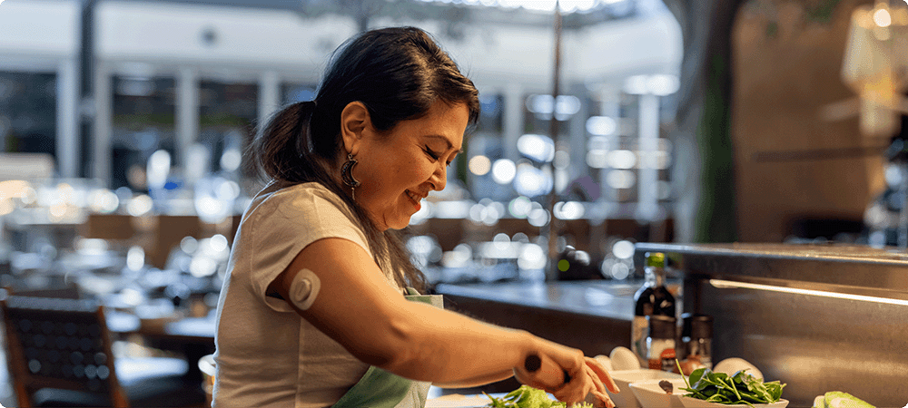Woman cooking while wearing the Dexcom G7 Sensor