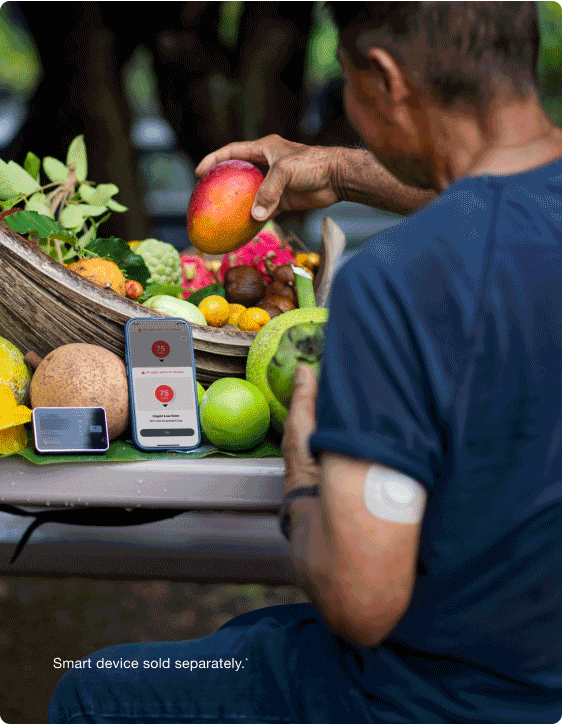 person putting fruit in a basket while checking their low glucose alert on thier phone