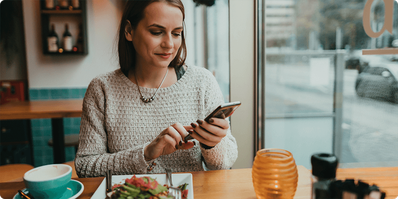 Woman checking her phone about to eat a salad 